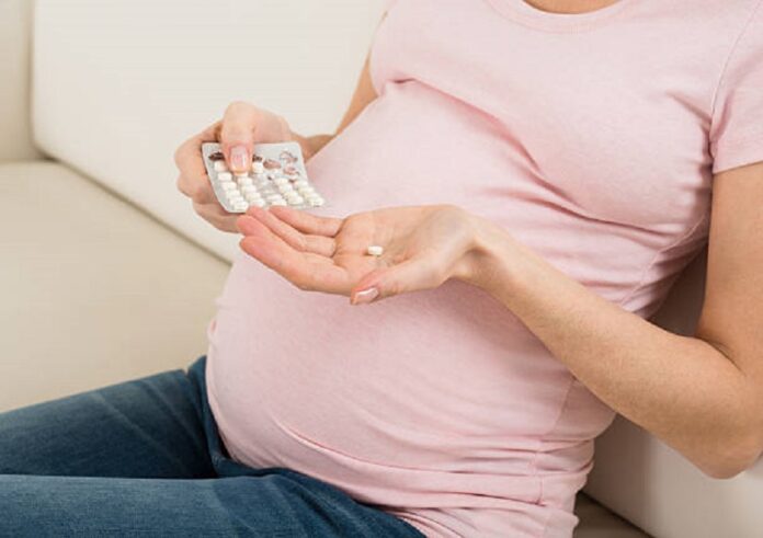Close-up Of Pregnant Woman Taking Vitamin Pill