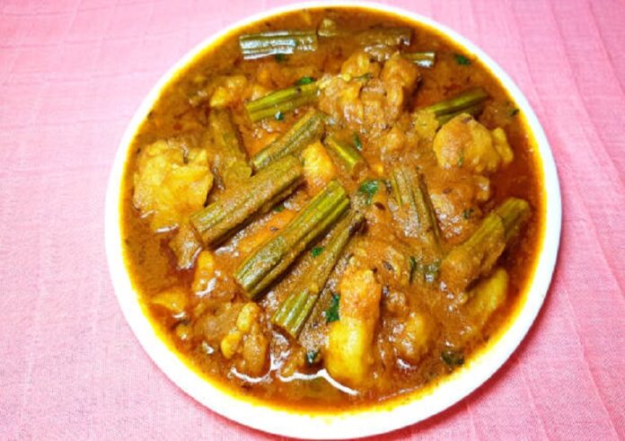 Drumstick Potato Curry in thick gravy in white plat on light background.